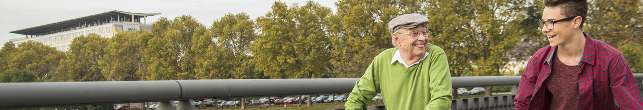 Meneer loopt met rollator en de kleinzoon is op het skateboard