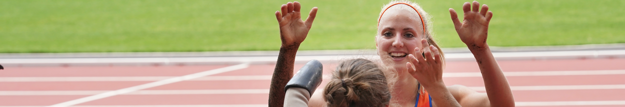 Twee dames die elkaar een high five geven op de atletiekbaan