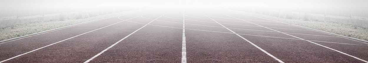 Atletiekbaan voor het rennen van de afstanden, met witte lijnen en mist die in de lucht hangt