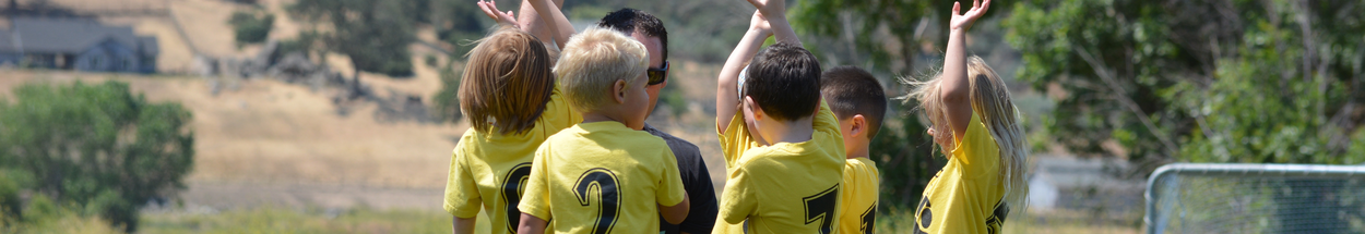 Team van jongetjes die voetballen en juichend bij de coach staan